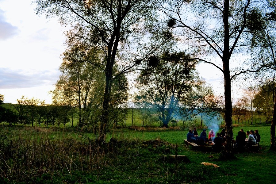 Corporate group enjoy a barbecue and camp fire near Carlisle, Cumbria